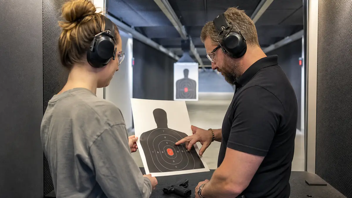 Metro Detroit instructor reviewing a paper target with a student during confidence-building range practice